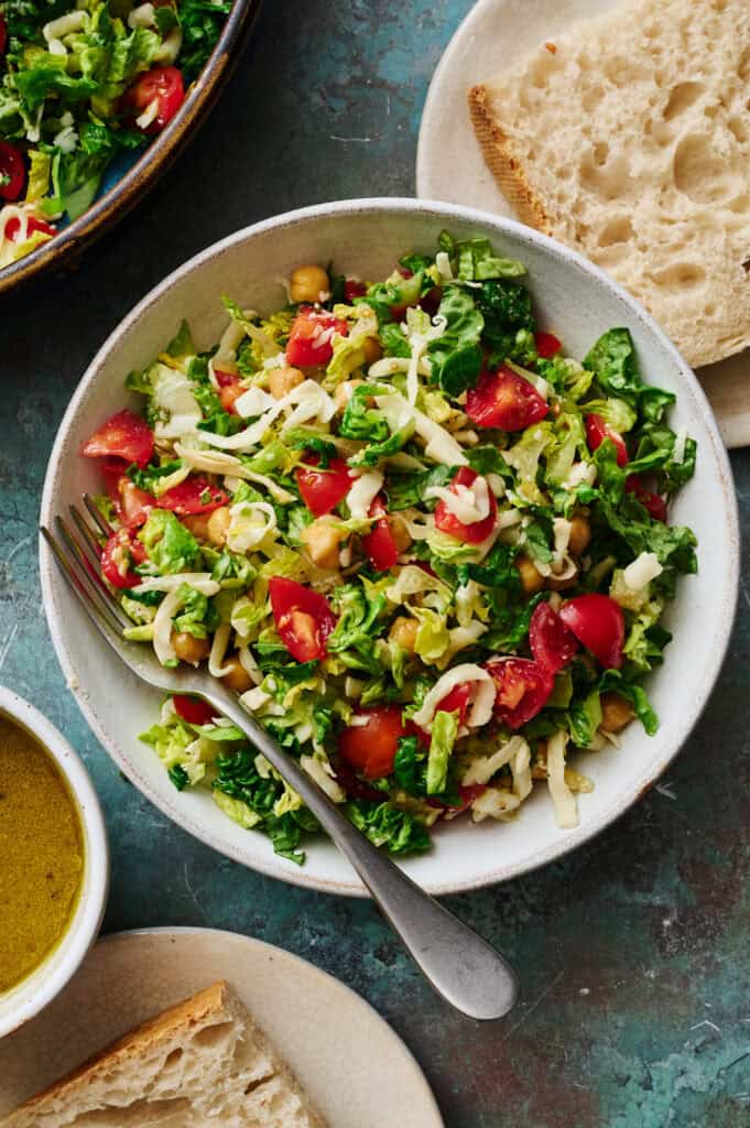 a single serving of caprese chopped salad with mozzarella, lettuce, garbanzos, basil and tomatoes