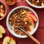 overhead view of a bowl of apple pie granola with milk and apple slices