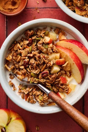 overhead view of a bowl of apple pie granola with milk and apple slices