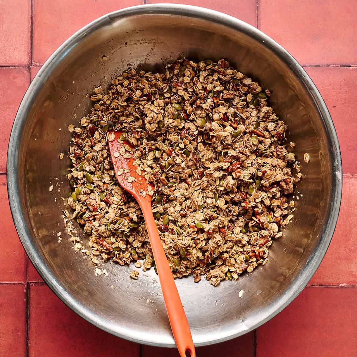 The wet and dry ingredients combined in a large metal bowl with a spatula