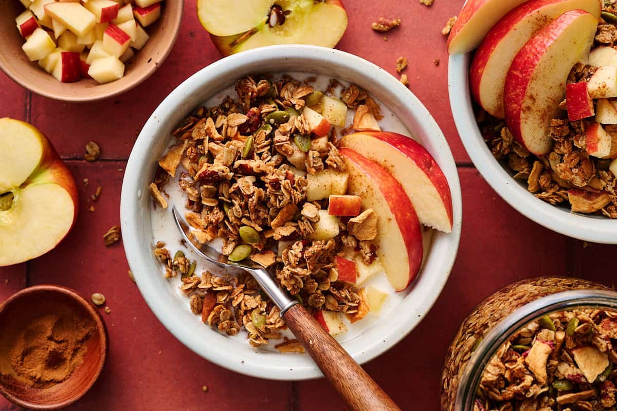 apple pie granola in a bowl with apple slices and milk