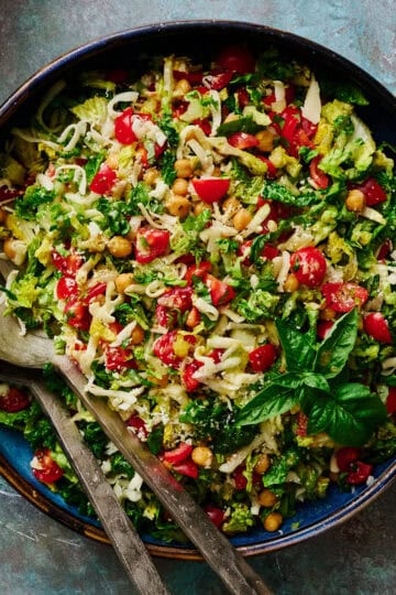 a large serving bowl filled with caprese chopped salad including mozzarella, basil and tomatoes