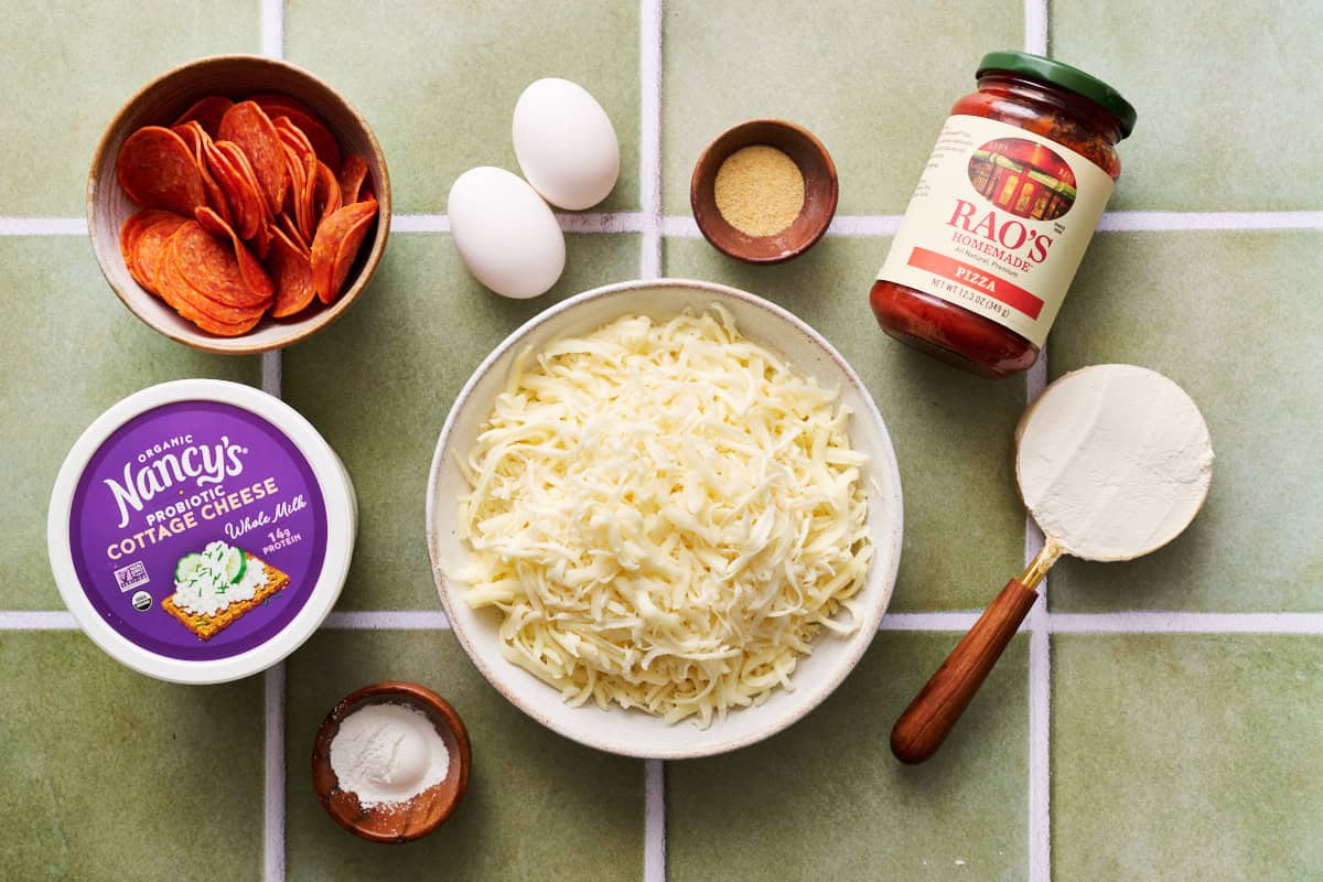 ingredients for making cottage cheese pizza crust including cottage cheese, mozzarella, pizza sauce, flour, garlic powder, egg, pepperoni and baking powder