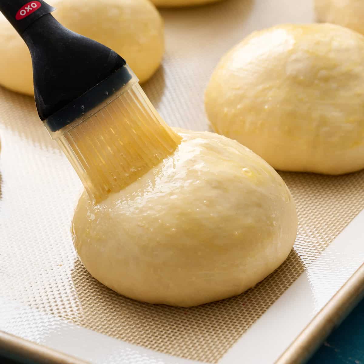 brushing egg wash onto a hamburger bun