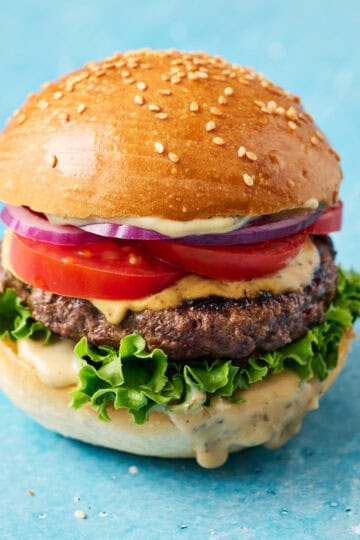 a hamburger loaded with meat, lettuce, tomatoes, onion and special sauce