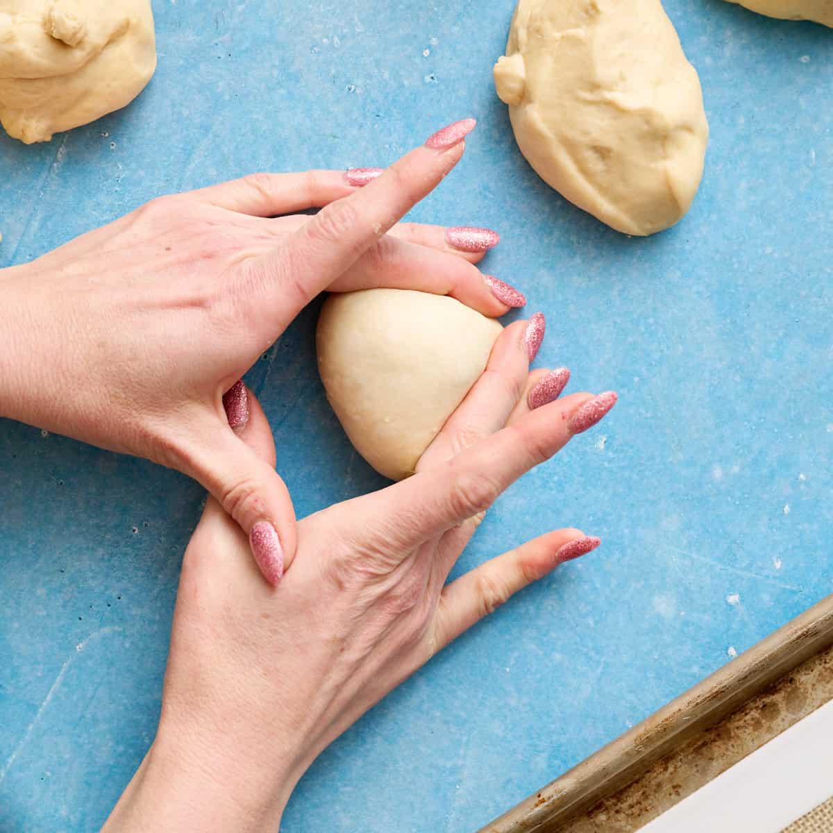 rolling a dough ball into shape by creating tension on the outside of it