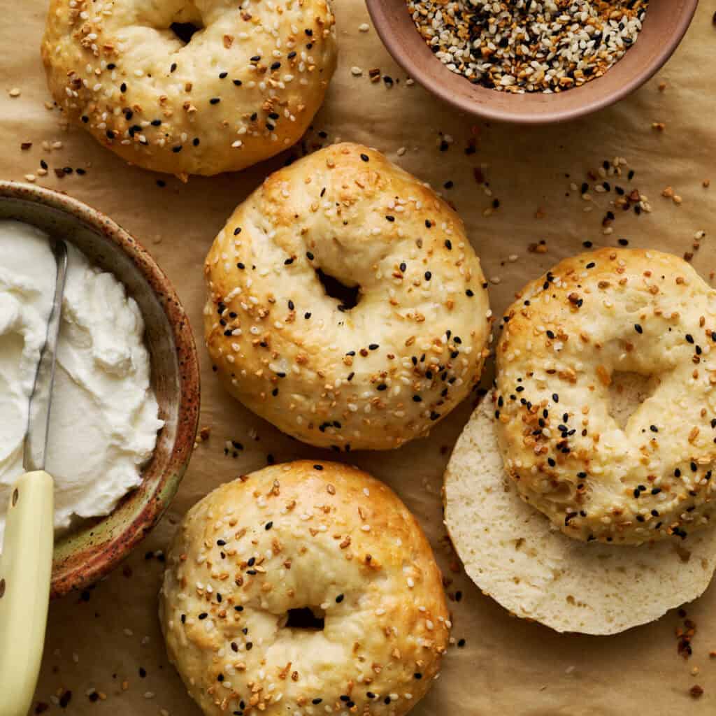 The bagels on a piece of parchment paper with cream cheese on the side