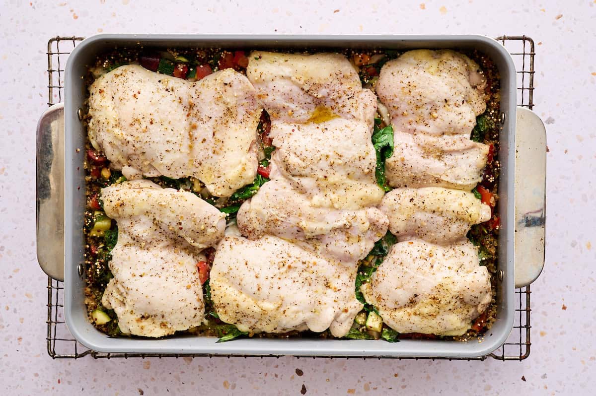 Chicken thighs after being cooked in a baking dish on a cooling rack.