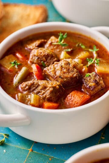 slow cooker beef stew in a white bowl with bread on the side