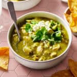 bowl of chile verde with chicken, cilantro and avocado with chips on the side