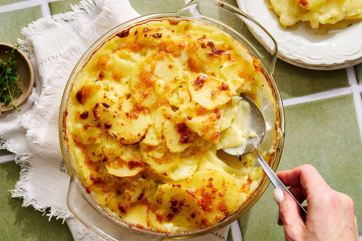 a dish of scalloped potatoes with a serving spoon in it