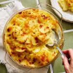 a dish of scalloped potatoes with a serving spoon in it