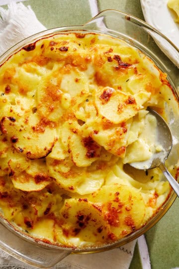 a dish of scalloped potatoes with a serving spoon in it