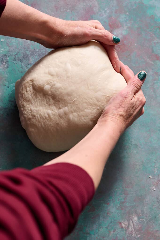 shaping the loaf of artisan sourdough bread after bulk fermentation
