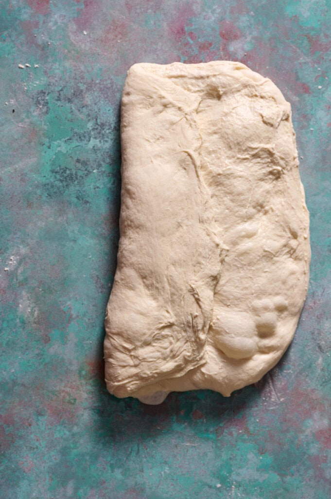folding half of the sheet of dough over toward the center to begin shaping