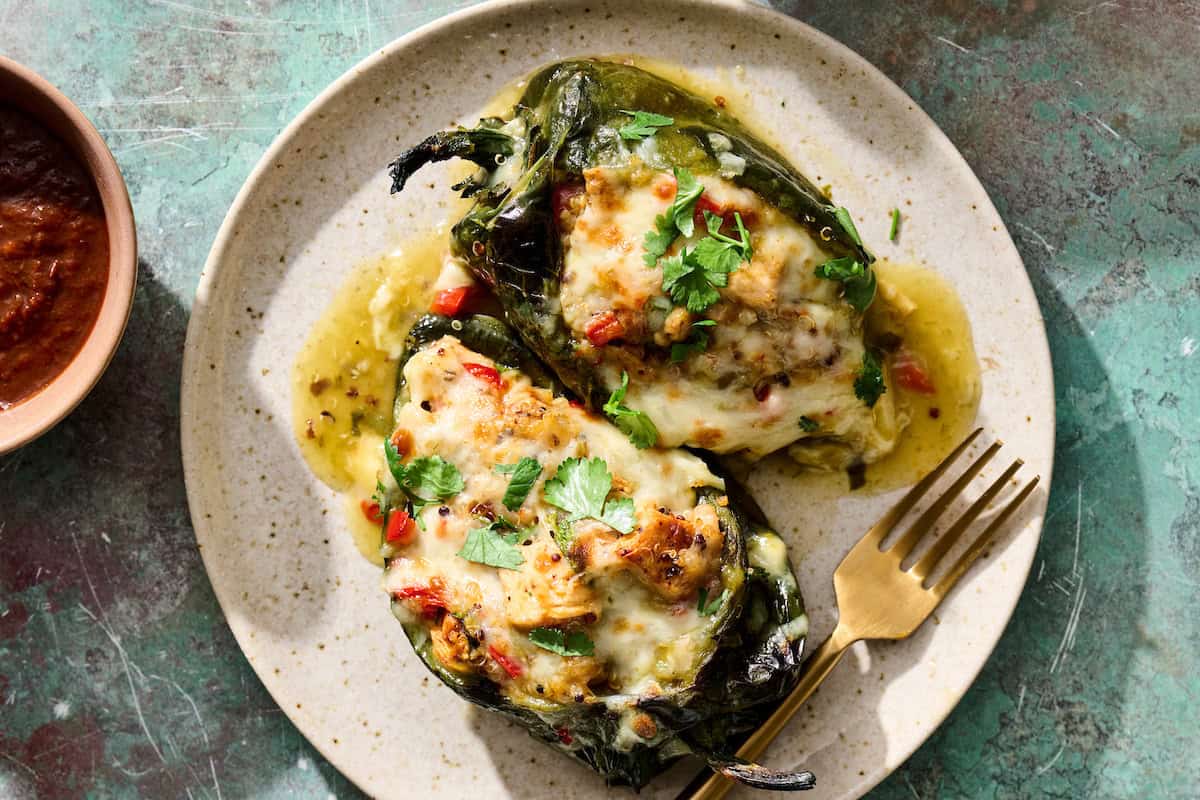 two chicken stuffed poblano peppers on a plate with a fork