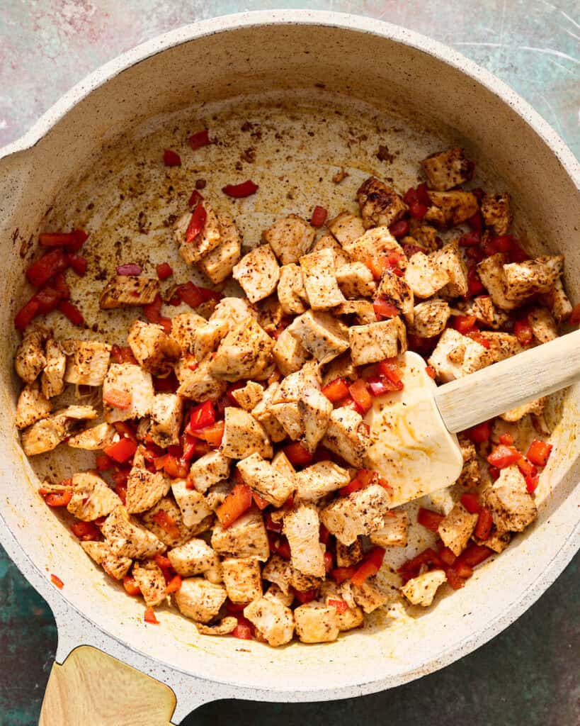 sauteeing diced chicken with bell pepper and spices