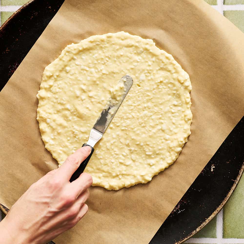 spreading the cottage cheese dough on parchment paper