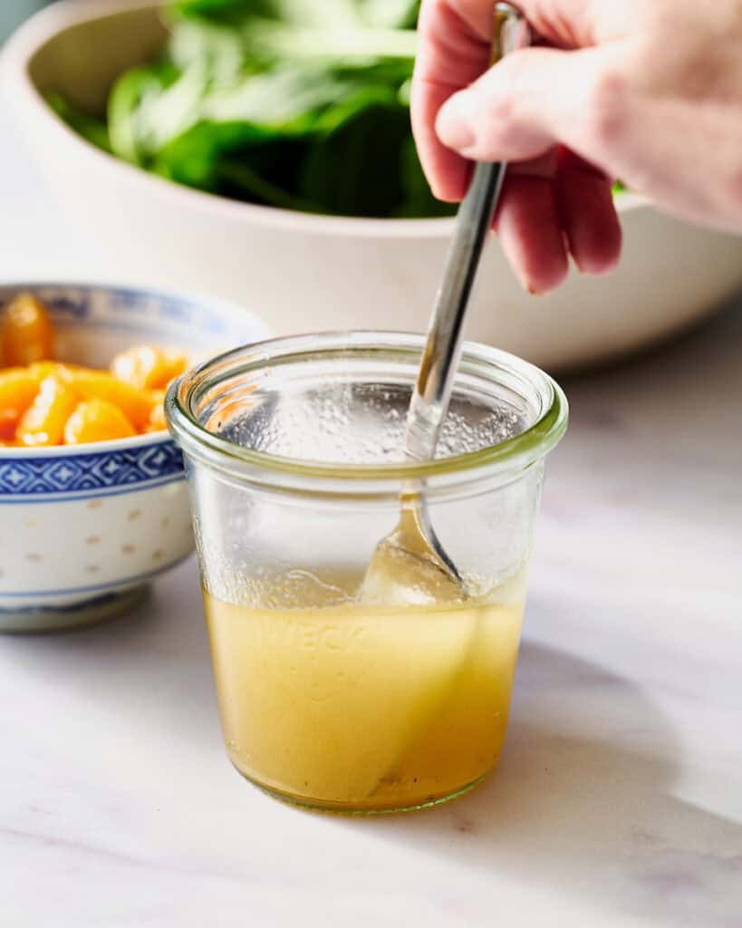 stirring homemade dressing in a glass jar
