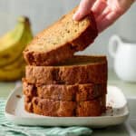 hand lifting a slice of sourdough banana bread