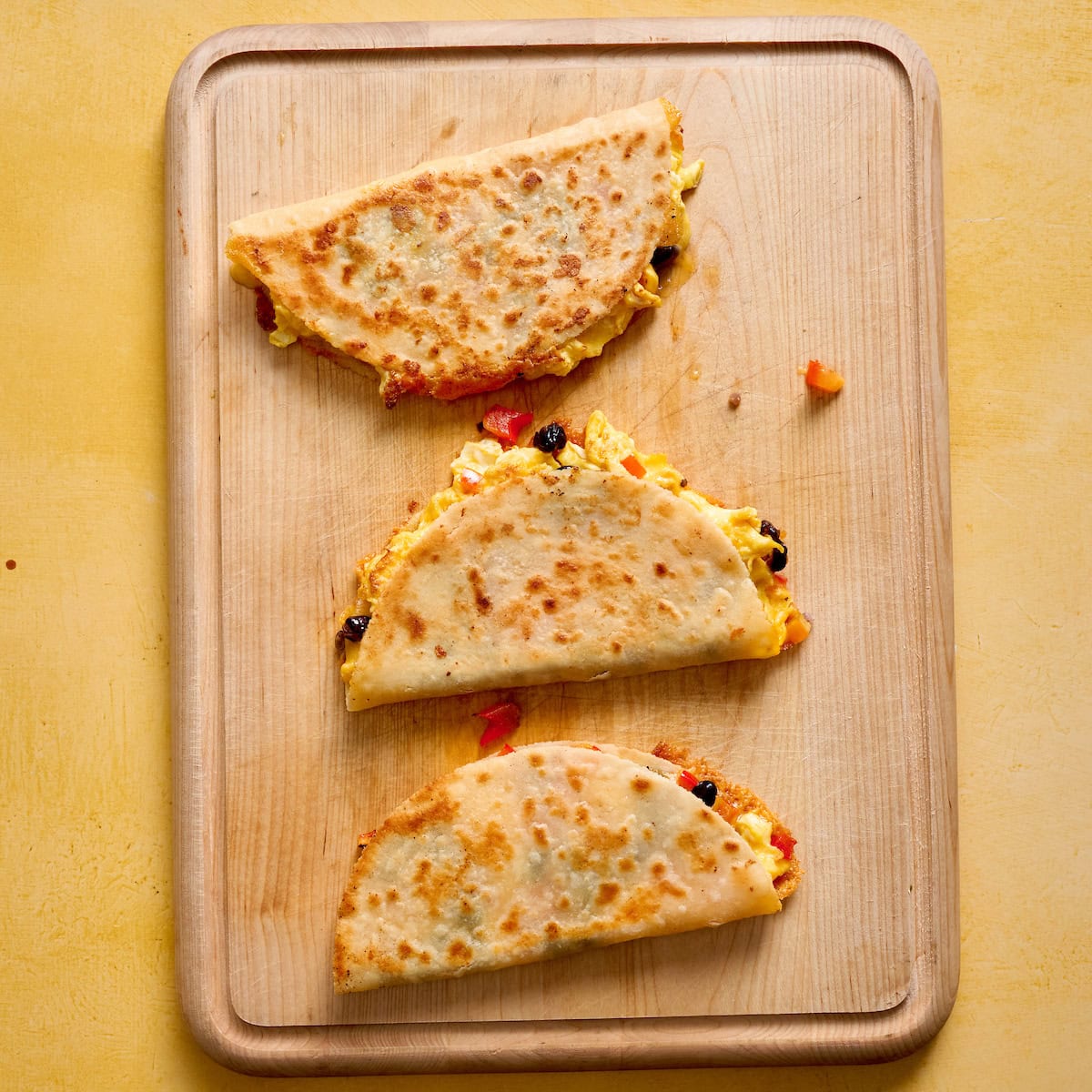 breakfast quesadillas on a cutting board before slicing in half to serve