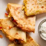 breakfast quesadillas served on a plate with greek yogurt, salsa and guac