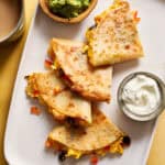 breakfast quesadillas served on a plate with greek yogurt, salsa and guac