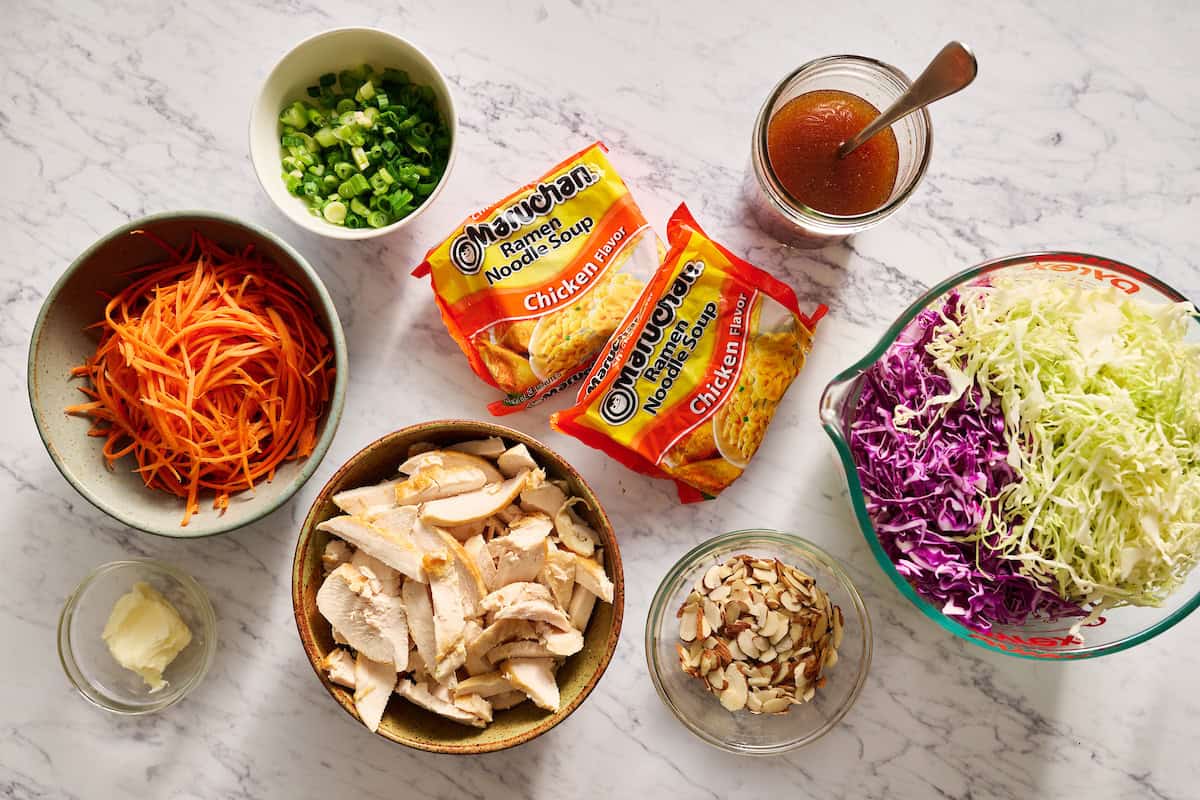 ingredients to make ramen noodle salad including chicken, cabbage, carrots, almonds and scallions