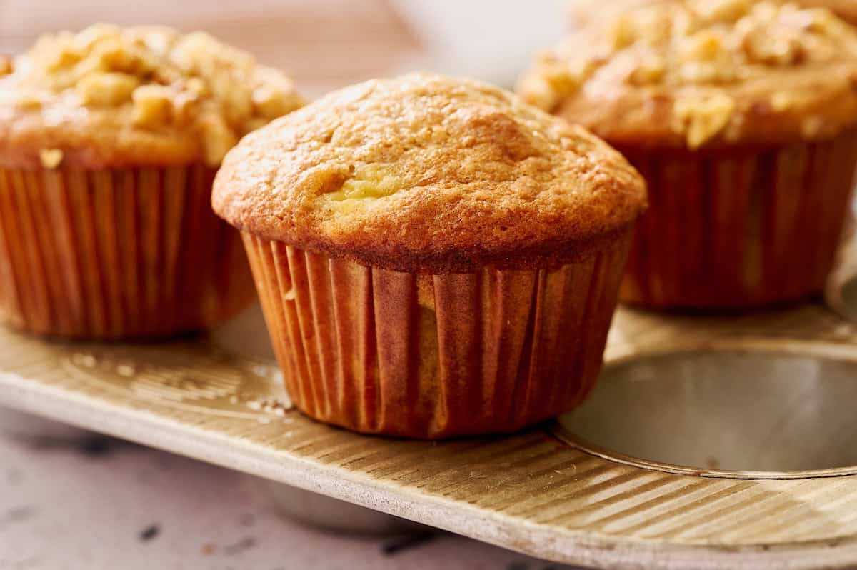 Sourdough discard banana nut muffins with golden domed tops on a muffin tin