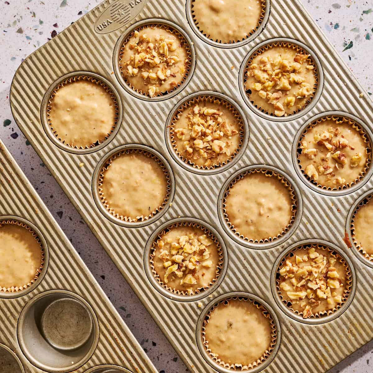 muffin batter poured in muffin liners and topped with nuts