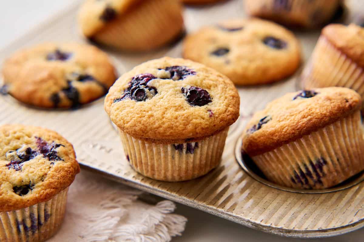 golden sourdough blueberry muffins resting on a muffin tin