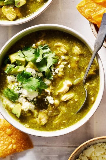 Bowl of chicken chili verde topped with cilantro served with chips